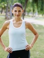 portrait of a young woman standing with arms akimbo in a park