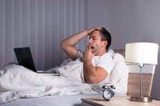 Man With Laptop On Bed Yawning