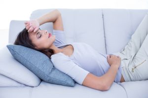 Sick brunette lying on the couch in the living room