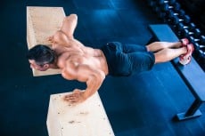 Muscular man doing push ups on fit box
