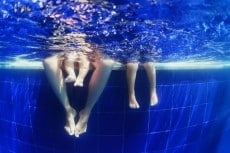 Underwater photo of happy family swimming in the blue pool