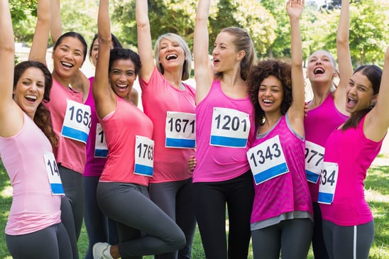 Excited female breast cancer marathon runners cheering in park