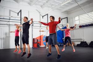 Group of people doing jumping jacks at gym