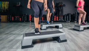 People legs over steppers training in aerobic class