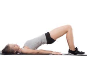 Young sporty beautiful woman doing fitness training on mat, bridge exercise for abs, back and shoulders, full length isolated studio image on white background