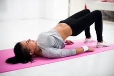 Bridge pose sporty woman doing warming up exercise for spine, backbend, arching stretching her back  working out at home fitness workout yoga gymnastics concept