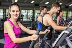 Fit people on elliptical bike at gym