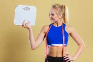 sporty happy woman with scale, weight loss