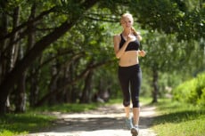 Running woman in park in summer training. Asian sport fitness model in sporty running clothes.