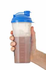 Man's fist holding the post workout chocolate whey protein shake
