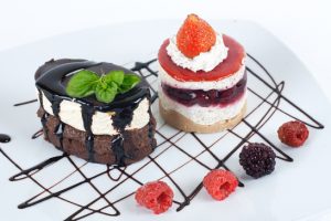 Desserts with chocolate topping and fruit on the plate.