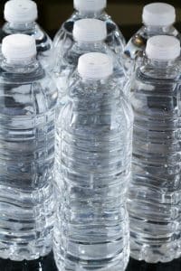 A row of plastic bottles of water on black background