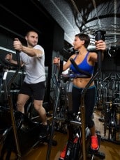 elliptical walker trainer man and woman at black gym