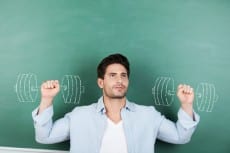 Teacher With Clenched Fists Against Dumbbells Drawn On Chalkboar