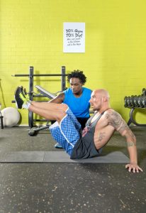 Personal fitness trainier motivating a client, during his workout in a gym, training his abs