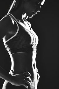 Portrait of slim female in activewear standing in isolation