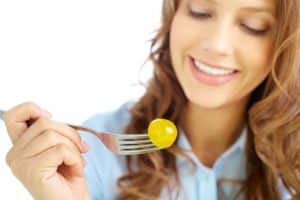 Close-up of frsh cherry tomato on fork held by pretty girl