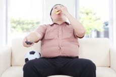 fat business man drinking beer  and sitting on sofa to watch TV