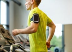 man with smartphone exercising on treadmill in gym