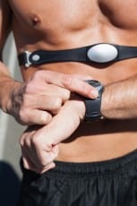 Athletic man on open road with monitor around chest on a sunny day