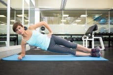 Fit brunette doing pilates on exercise mat at the gym