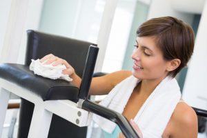 Fit brunette wiping down bench at the gym