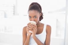 Cute sporty model drinking coffee in bright fitness studio
