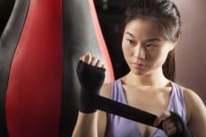 Young confident female boxer wrapper her wrists in the gym