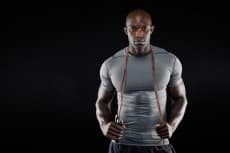 Handsome muscular man posing with jumping rope
