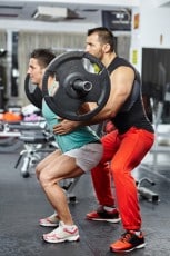Doing barbell squats with personal instructor