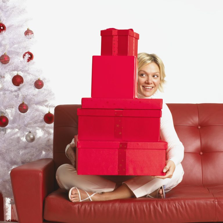 Young Woman Sitting on Sofa with Assorted Presents on Lap