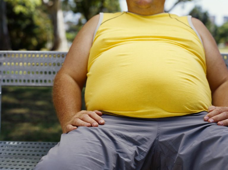 mid section view of a man sitting on a bench in a park