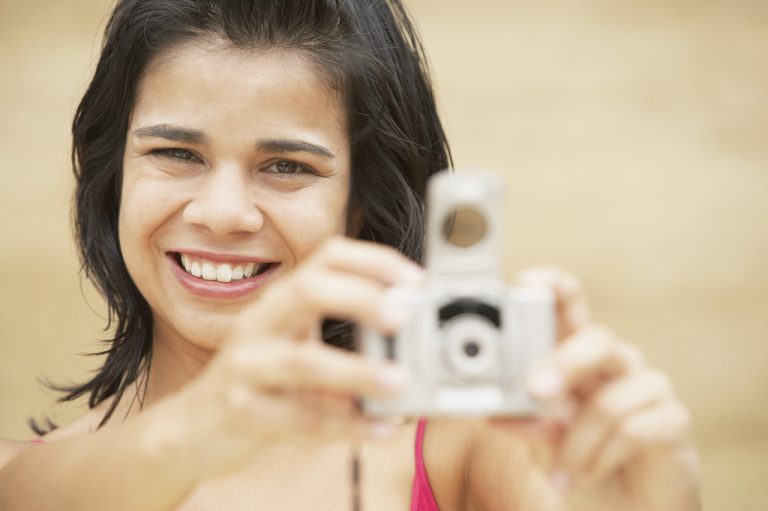Young woman holding digital camera