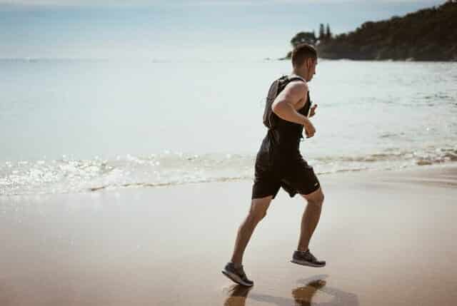 man-wearing-black-tank-top-and-running-on-seashore-1390403