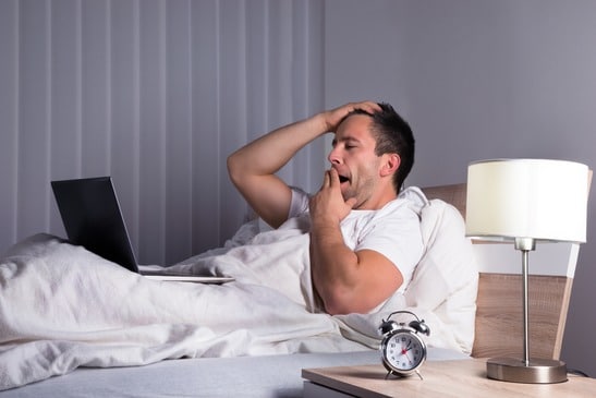 photodune-10219130-man-with-laptop-on-bed-yawning-xs