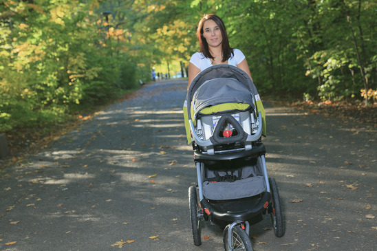 A young woman with a stroller walking in the park
