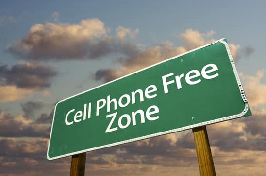 Cell Phone Free Zone Green Road Sign In Front of Dramatic Clouds and Sky.