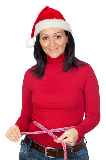 Beautiful girl with Christmas hat measuring her waist