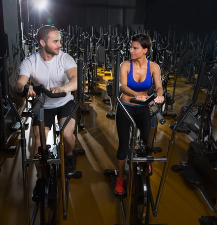 elliptical walker trainer man and woman at black gym