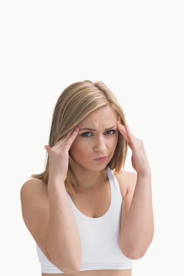 Portrait of young woman rubbing her temples over white background