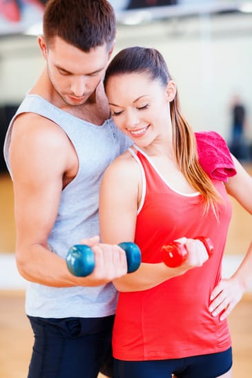 two smiling people working out with dumbbells