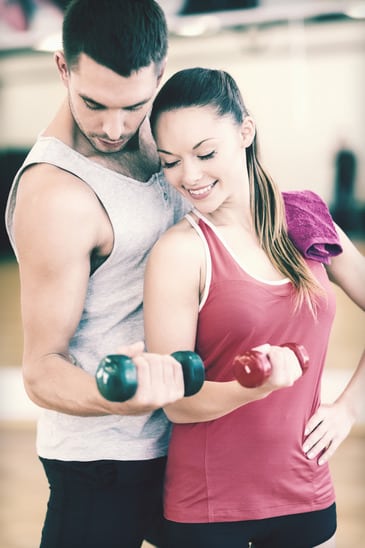 two smiling people working out with dumbbells