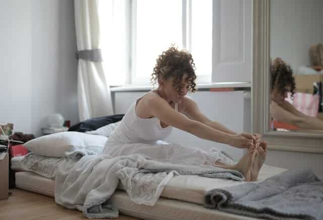 woman-in-white-tank-top-sitting-on-bed-3791607